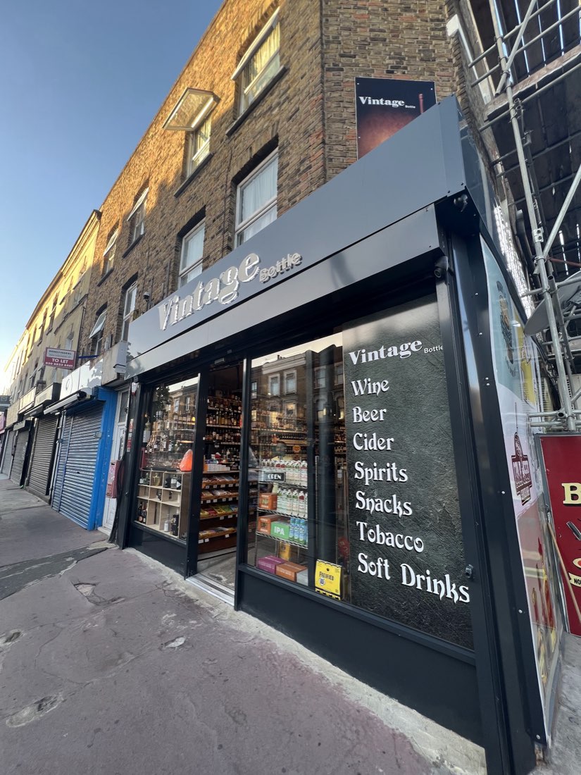 The Vintage Bottle shopfront on Chatsworth Road, Lower Clapton, its window listing Wine, Beer, Cider, Spirits, Snacks, Tobacco and Soft Drinks